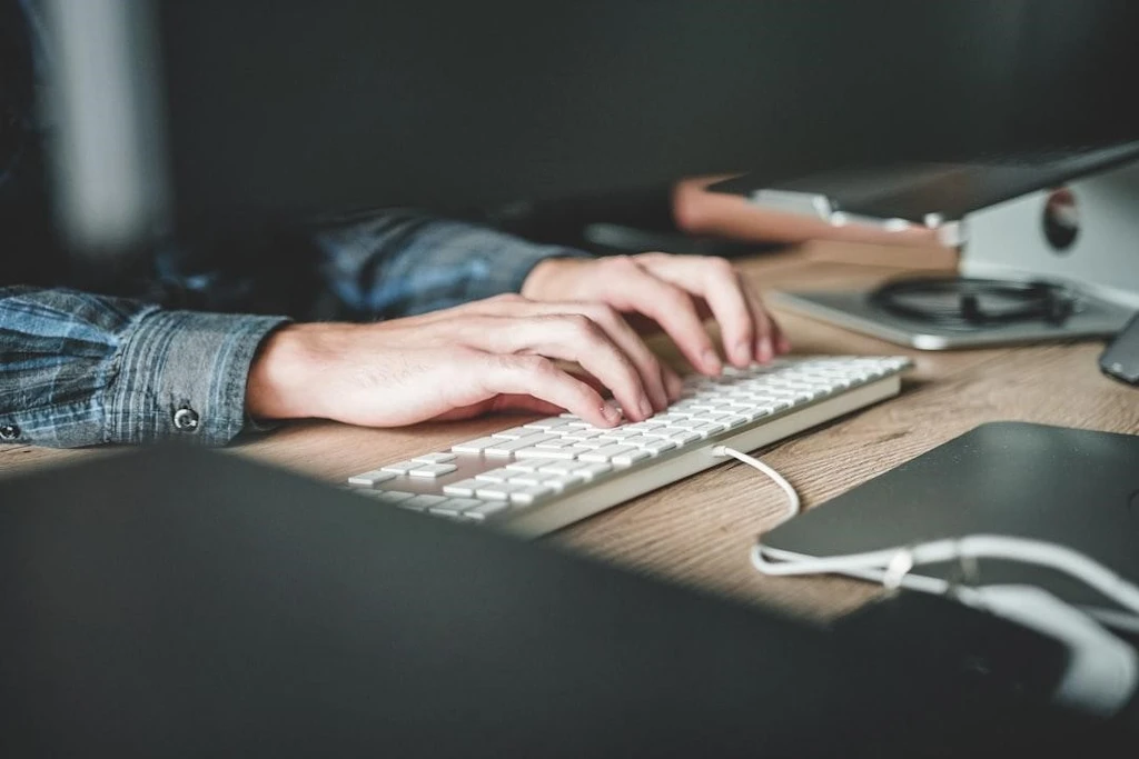 Two hands typing in the keyboard