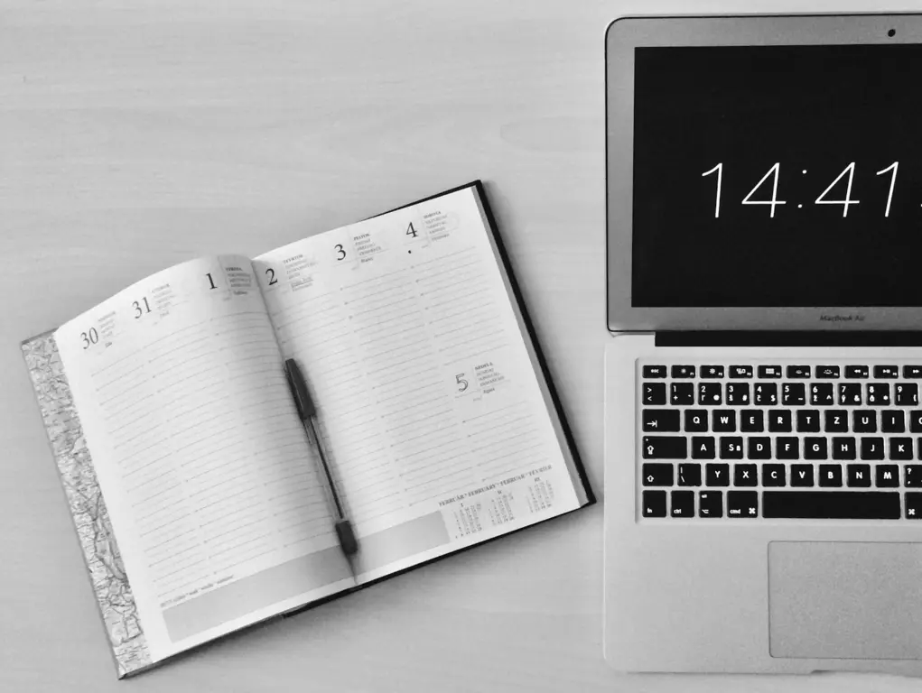 A laptop with notebook beside it