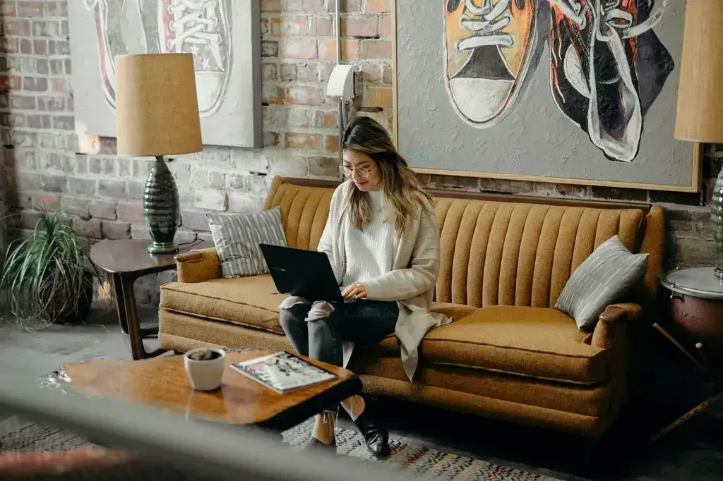 A woman sitting in the couch while working with her laptop