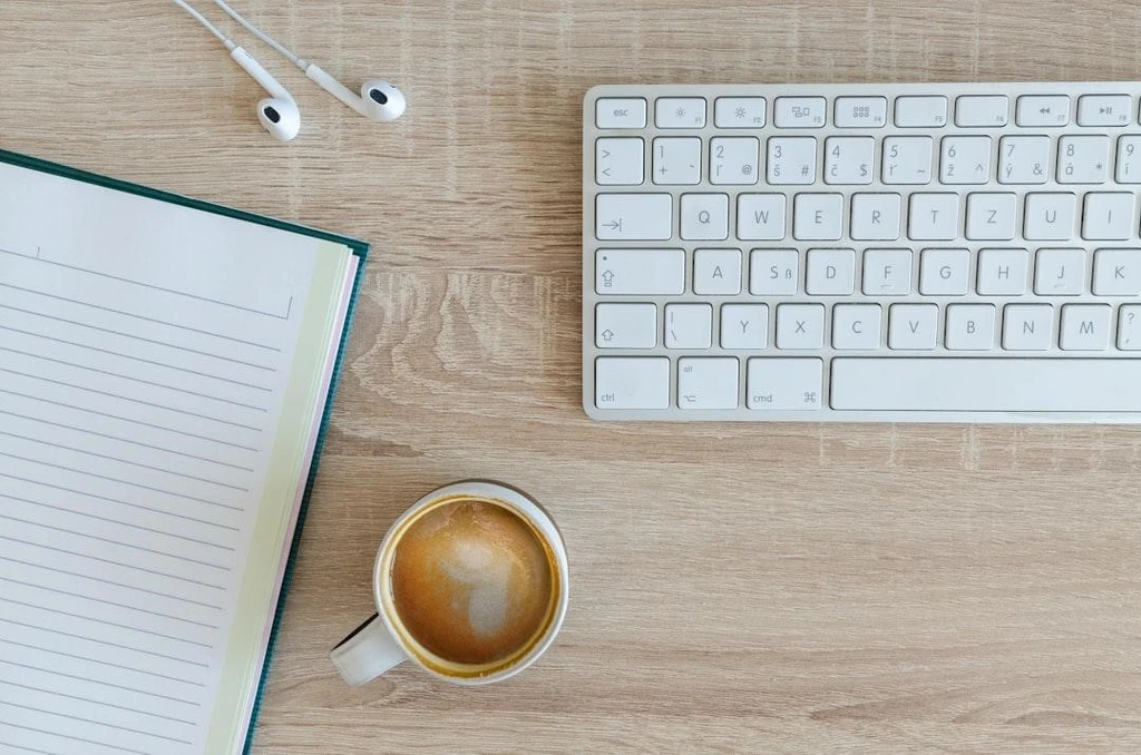Keyboard with notebook and a cup of coffee