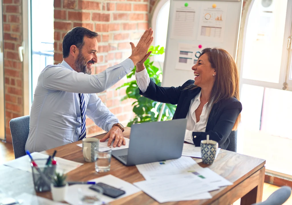 An image of a man and woman high-fiving in success