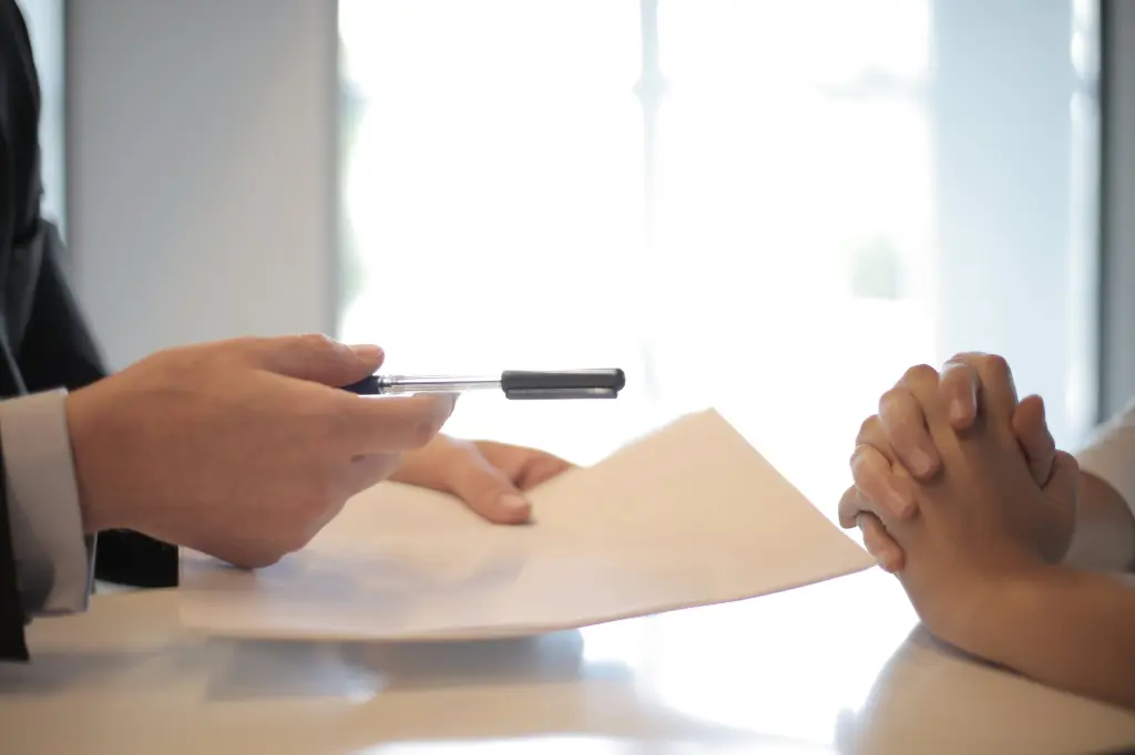 A man giving a pen and paper to sign