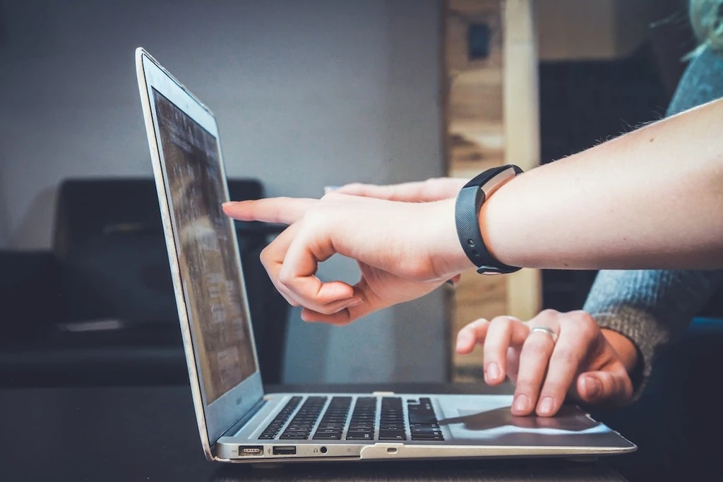 people pointing their fingers to the laptop screen