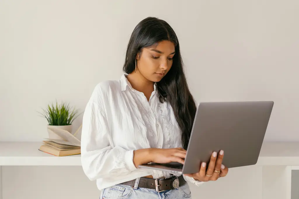 A woman standing while holding a laptop